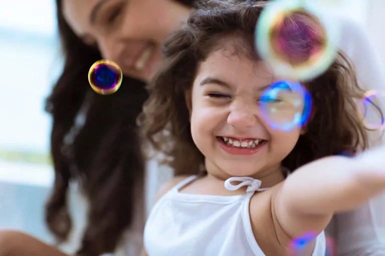 ABA technician blowing bubbles for a little girl, building relationship and trust.