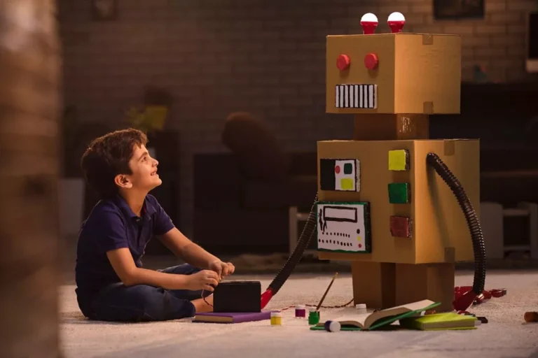 Small boy, creating cardboard robot showing his personal interests.